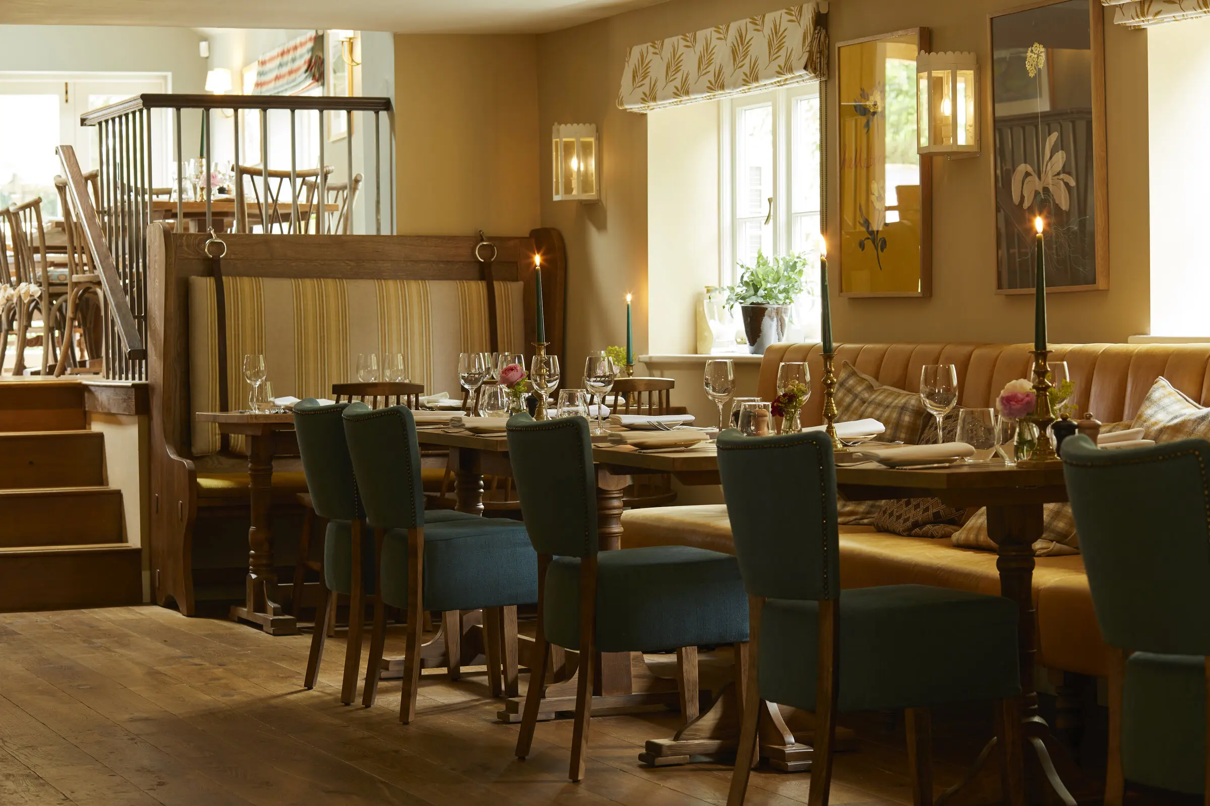 The long dining room, candles lit along tables of green velvet chairs