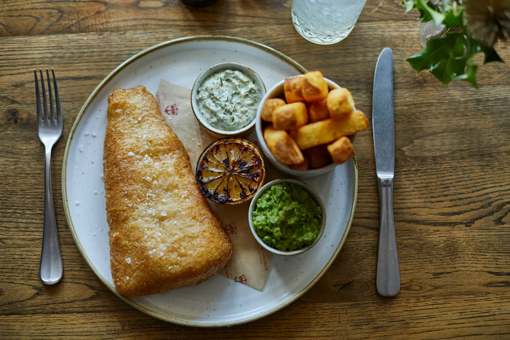 Beer-battered fish and chips with mushy peas, tartare sauce and a charred lemon half