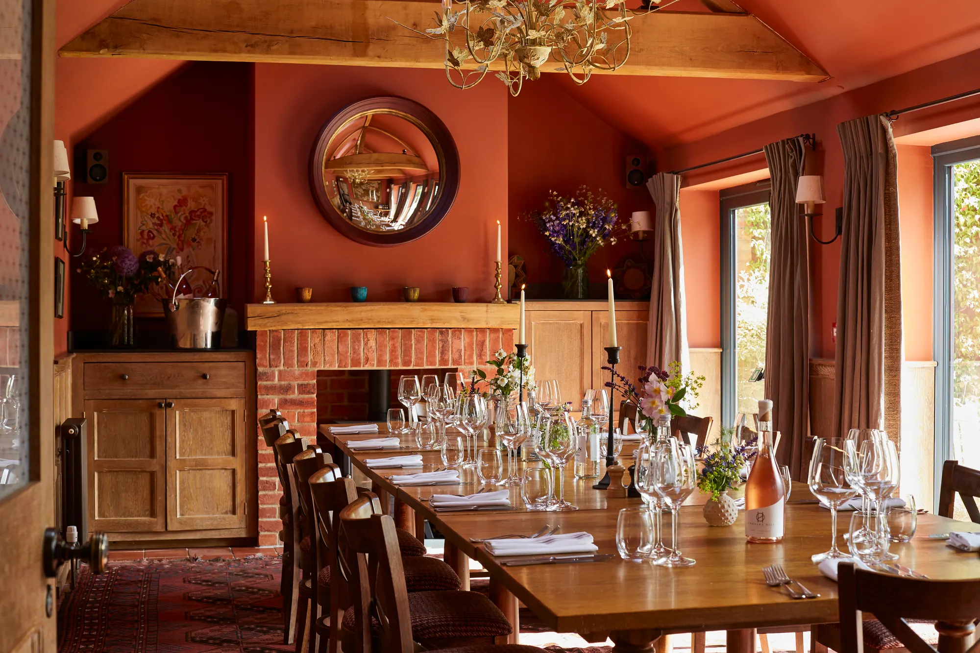 The Partridge Room, a terracotta-walled private dining room with a long table laid for a party and a brick fireplace