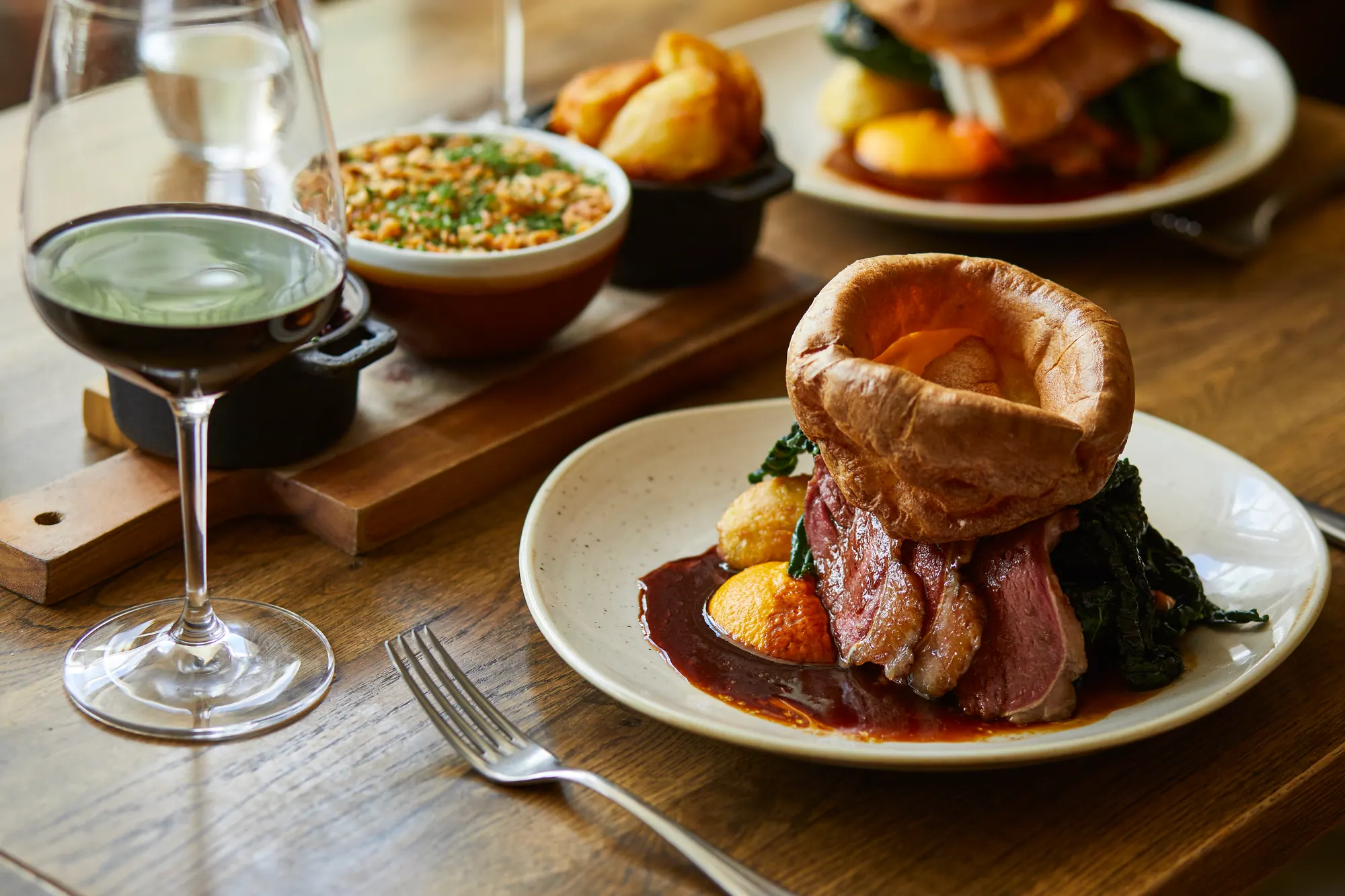 Sunday roast beef with a towering Yorkshire pudding, cauliflower cheese and red cabbage to share, with red wine