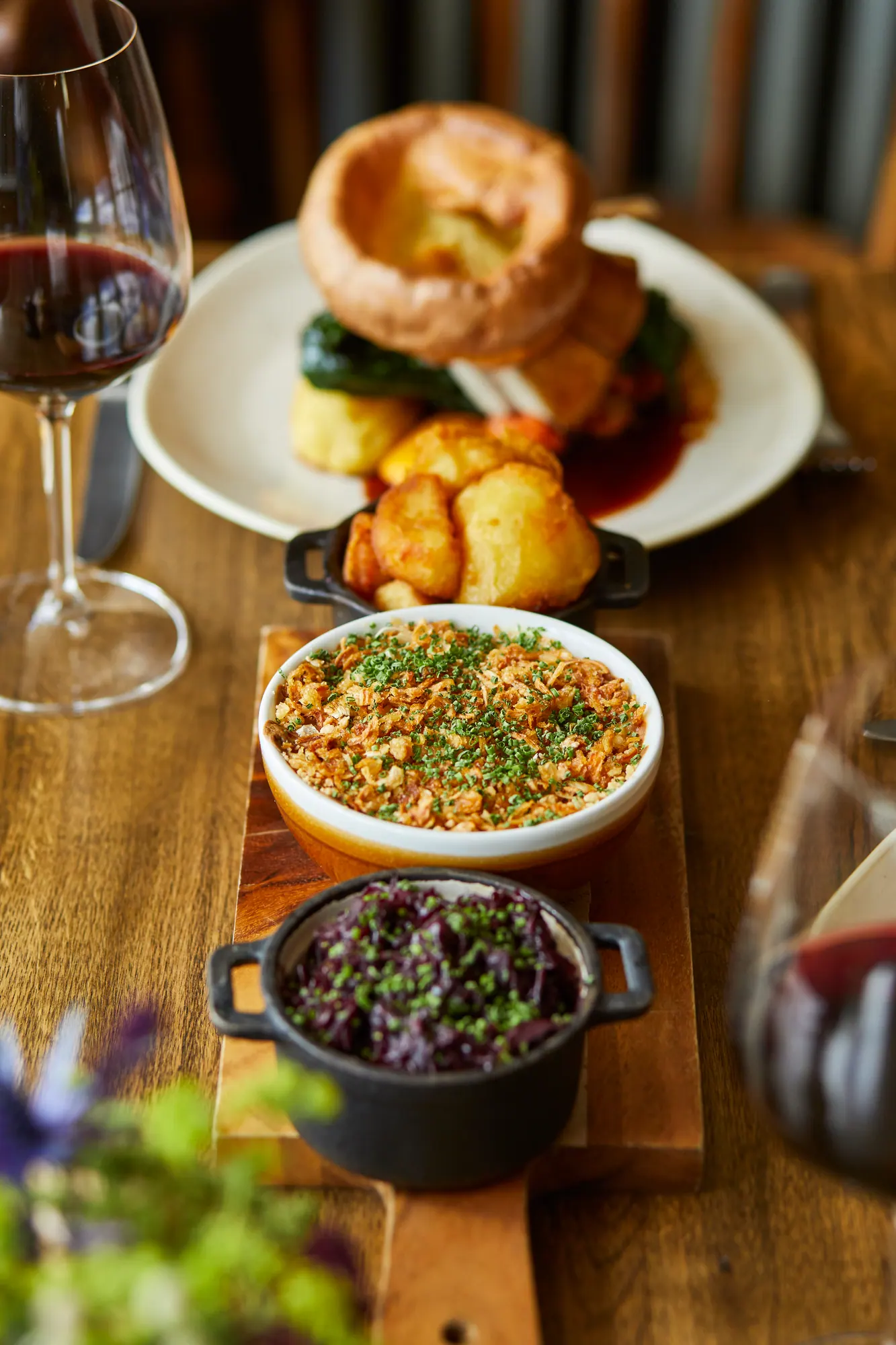 A Sunday roast with Yorkshire pudding and roast potatoes, sharing dishes of cauliflower cheese and red cabbage
