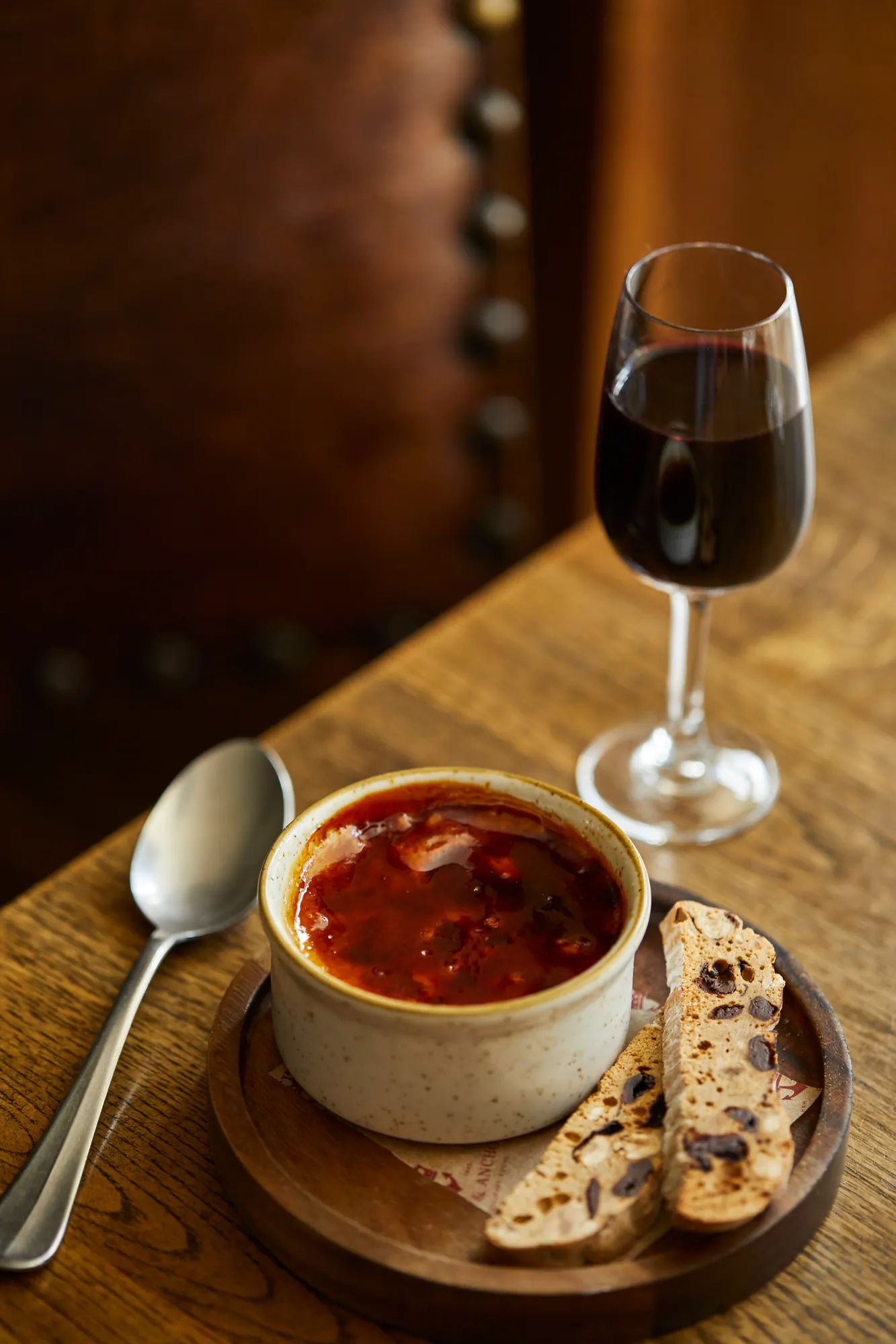 A rich stew in an earthenware bowl with crispbreads and a glass of red wine