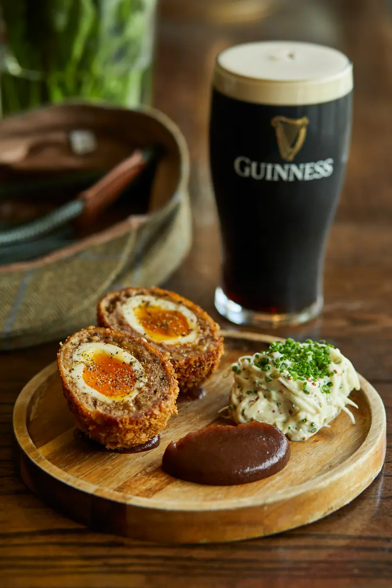 Halved Scotch eggs with soft orange yolks, celeriac remoulade and brown sauce, with a pint of Guinness