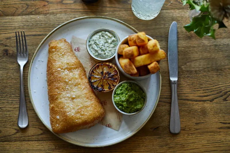 Beer-battered fish and chips with mushy peas, tartare sauce and a charred lemon half