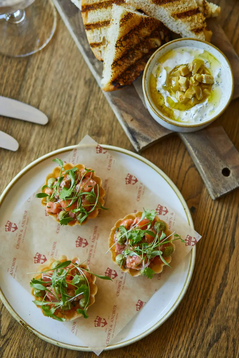 Three savoury tartlets topped with fresh herbs, with grilled toast and a whipped dip