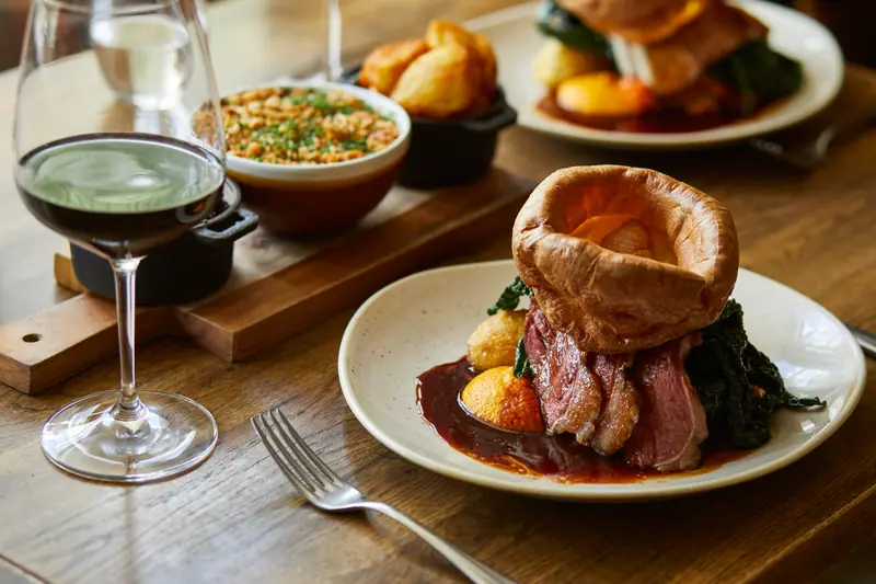 Sunday roast beef with a towering Yorkshire pudding, cauliflower cheese and red cabbage to share, with red wine