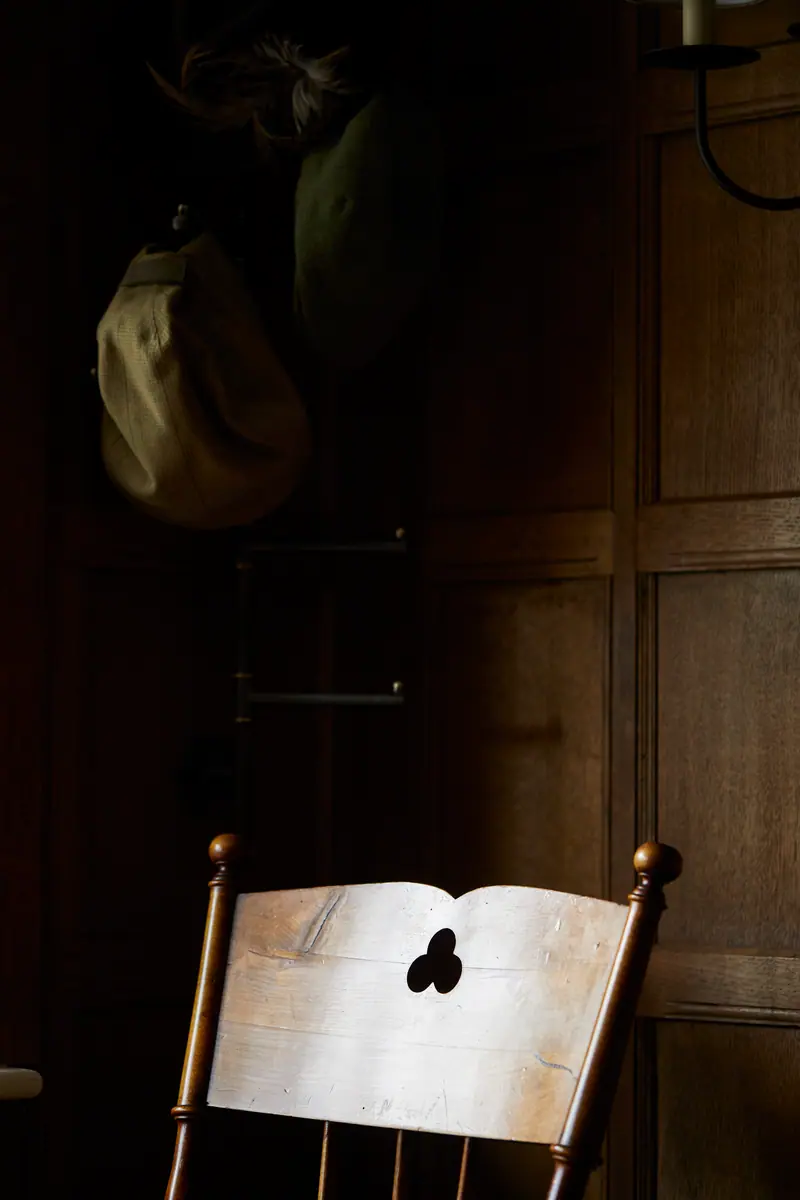 A wooden chair with a club cut into its back, in the low light of the panelled bar