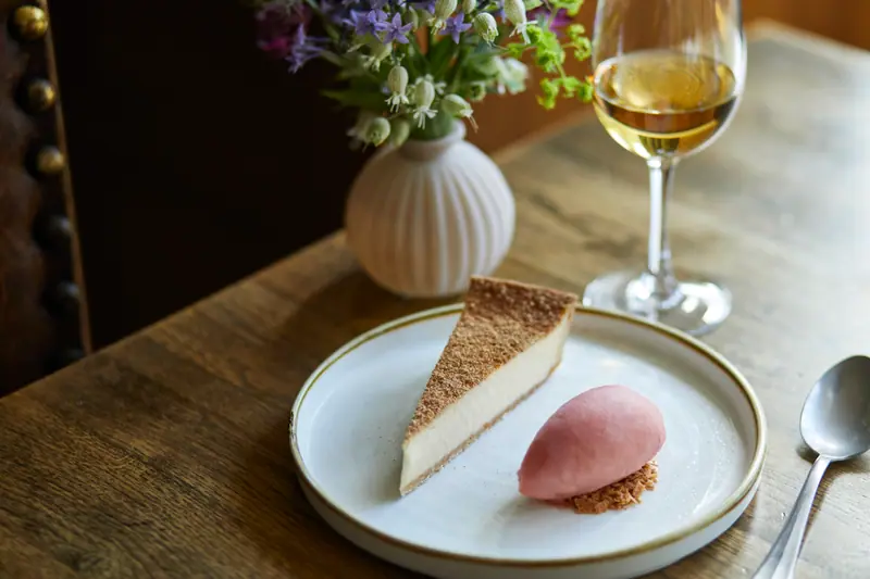 A slice of custard tart with a quenelle of pink sorbet and a glass of dessert wine